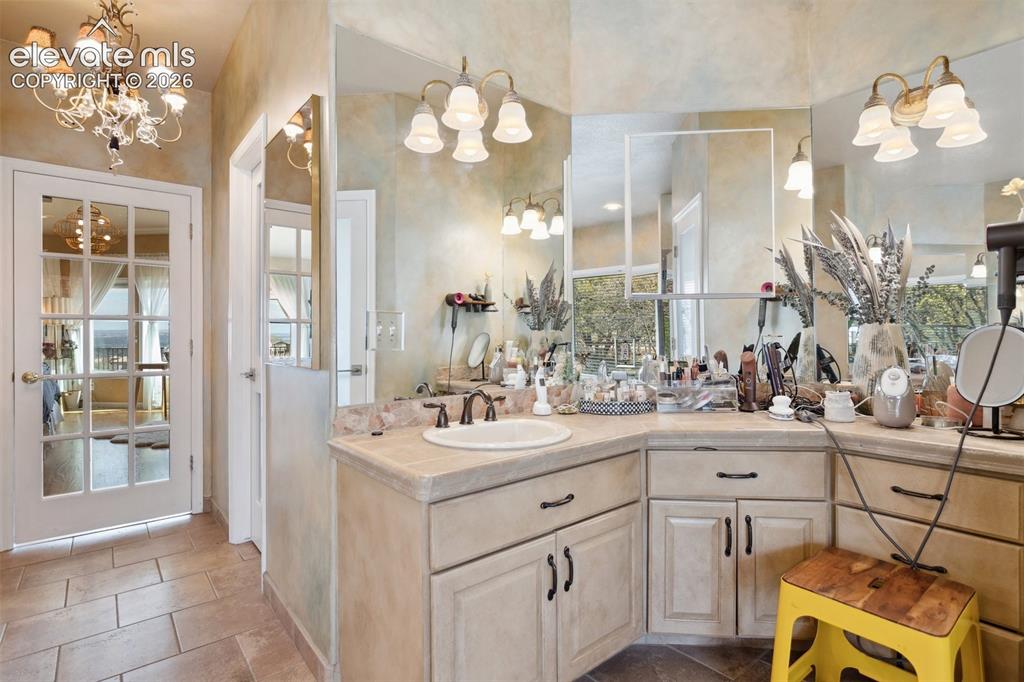 Image 32 of 50: Vanity area featuring a corner sink, light-toned countertop, and multiple w