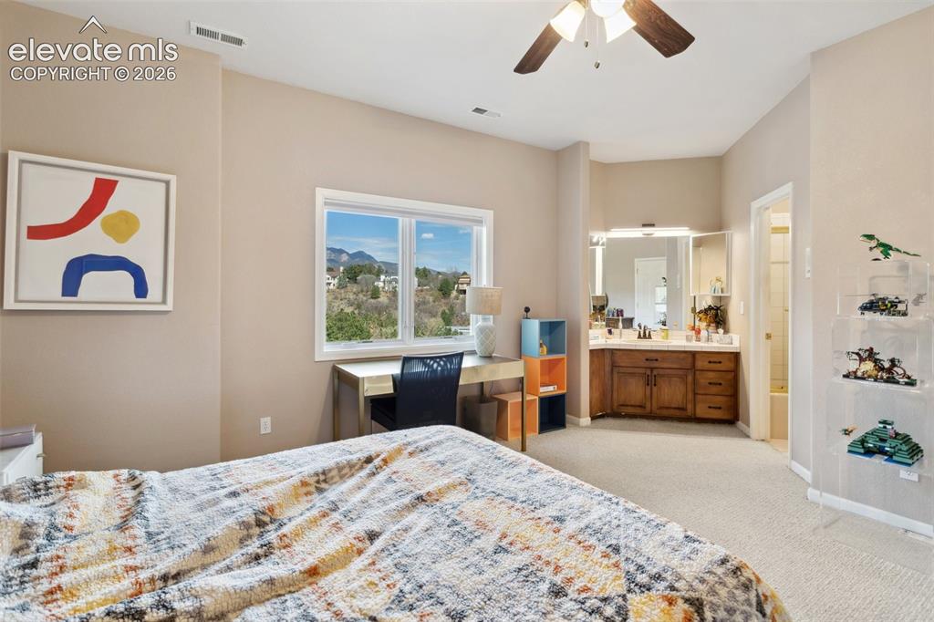 Image 34 of 50: Bedroom featuring a window with a mountain backdrop, a ceiling fan, and lig