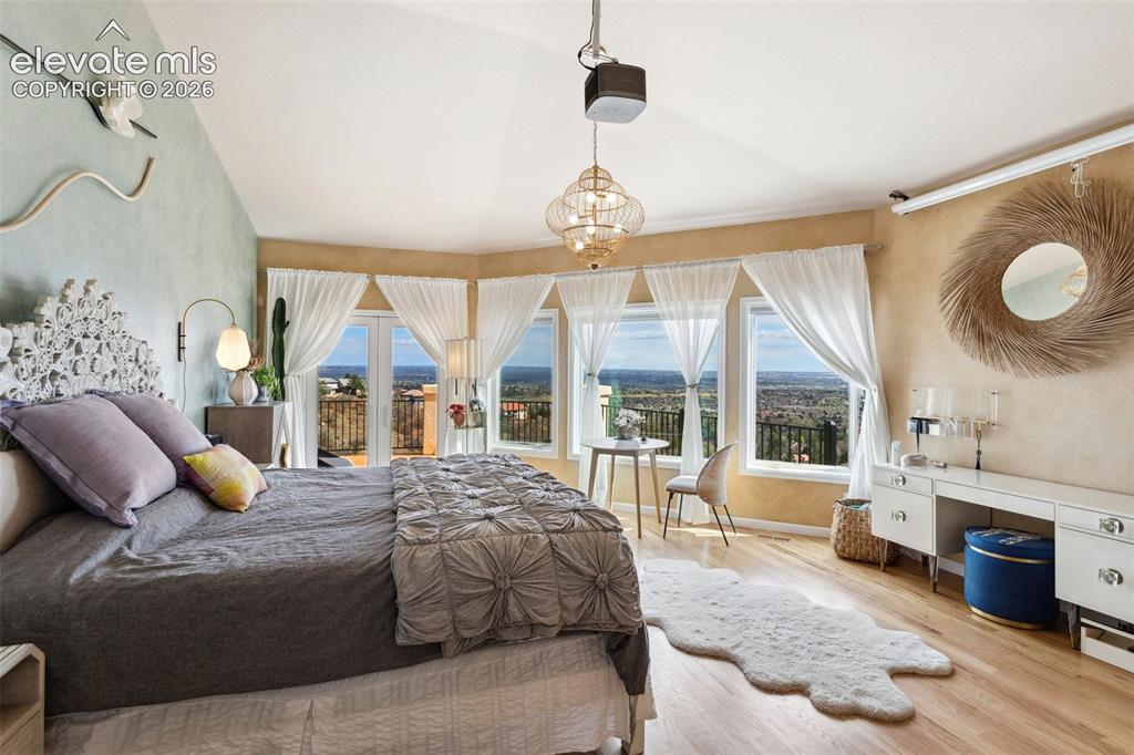Image 36 of 50: Vaulted ceiling bedroom featuring wood-finish flooring, a decorative chande
