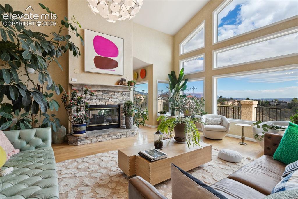 Image 9 of 50: Vaulted ceiling living space featuring a stone fireplace, wood-finish floor