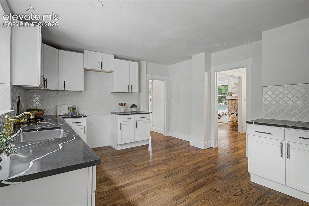 Image 14 of 38: Spacious kitchen featuring white cabinetry, dark countertops with distincti