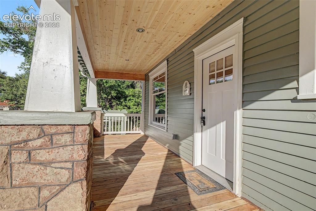 Image 2 of 38: Covered front porch featuring wood-finish flooring and a natural wood-plank