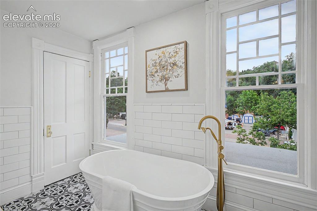 Image 20 of 38: Freestanding soaking tub with a floor-mounted brass faucet, complemented by