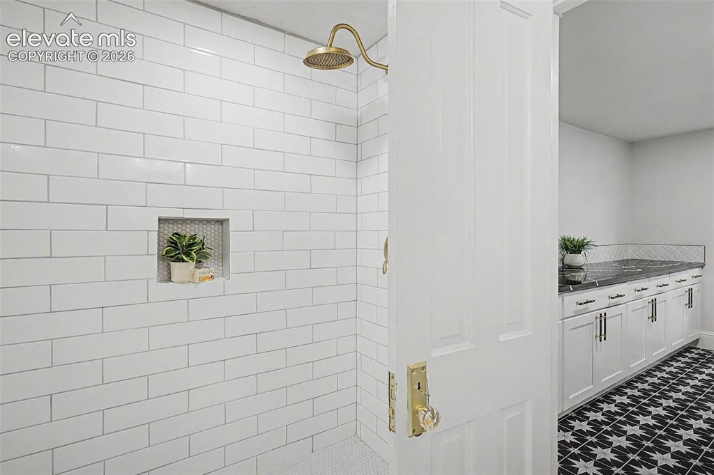 Image 21 of 38: Shower enclosure with white subway tile walls, a built-in niche with hexago