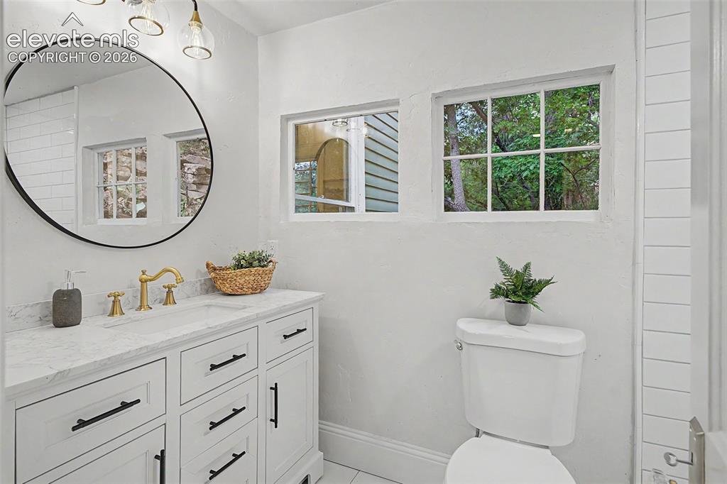 Image 22 of 38: Bathroom featuring a white vanity with black hardware, a marble-finish coun