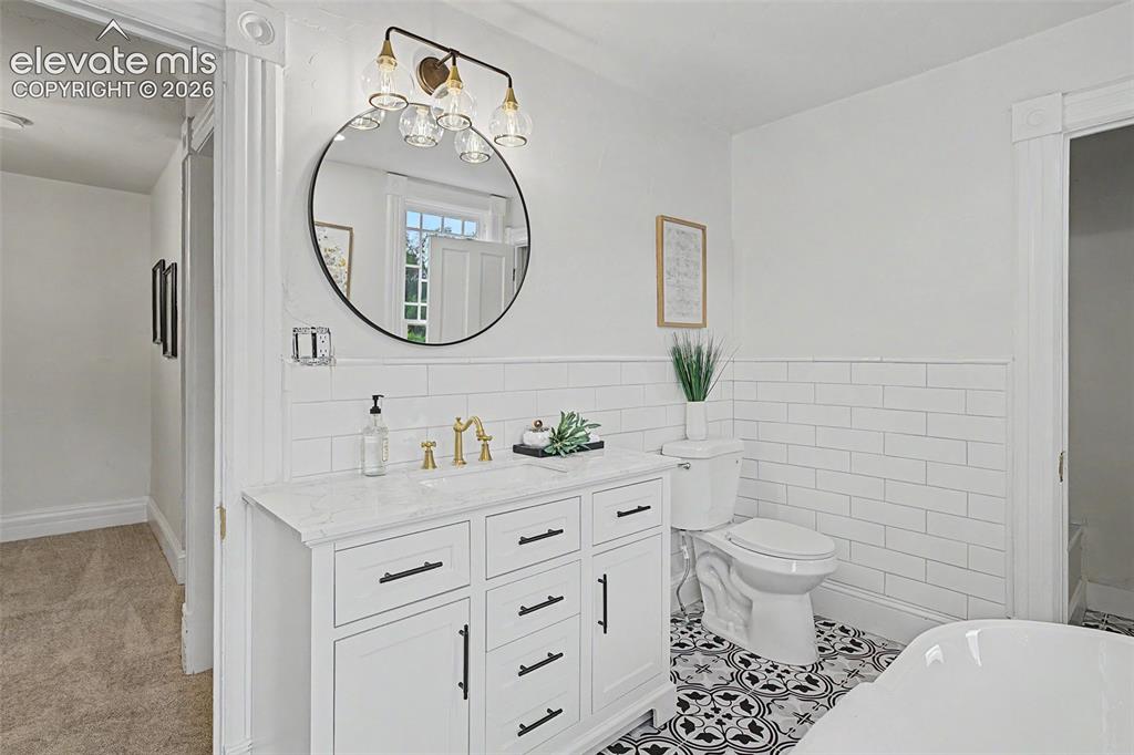 Image 23 of 38: Bathroom featuring a white vanity with a light-toned countertop, black hard