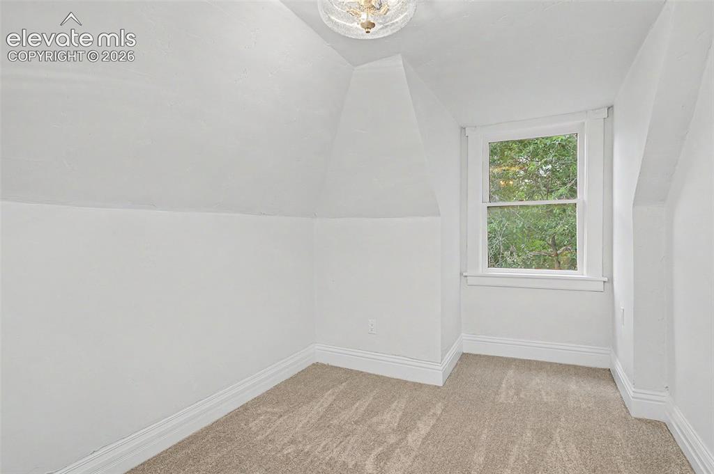 Image 24 of 38: Room featuring sloped ceilings, a single window with white trim, and neutra