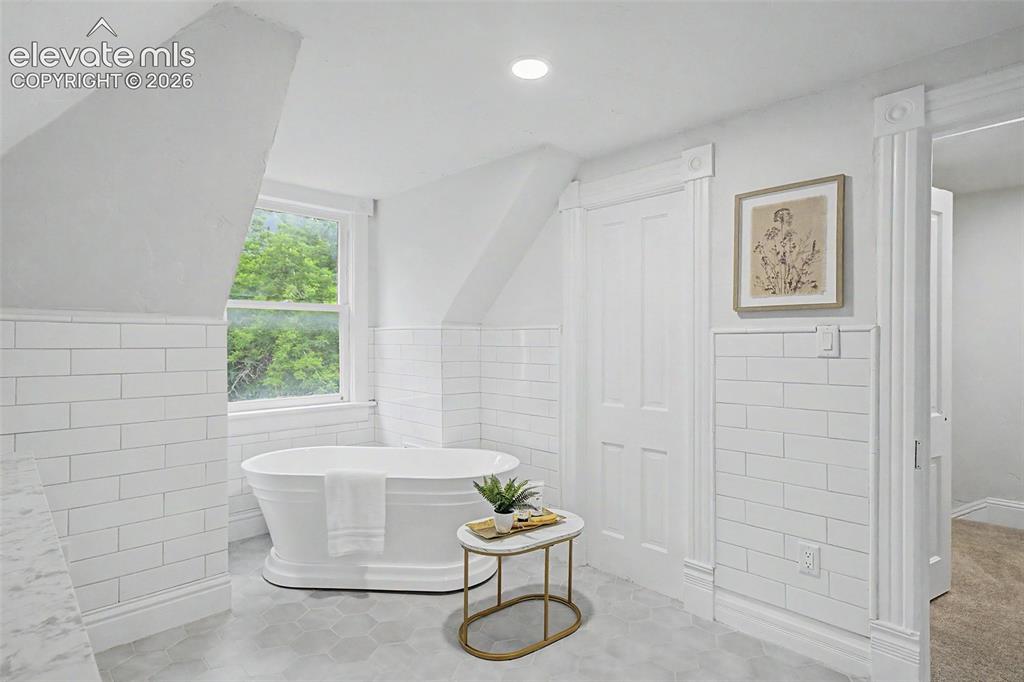 Image 26 of 38: Freestanding tub with subway tile wainscoting and hexagon floor tiles