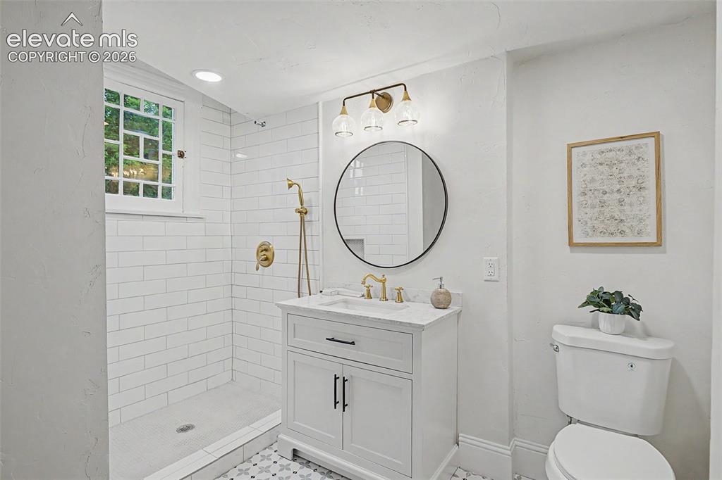 Image 27 of 38: Contemporary bathroom featuring a subway-tiled shower with gold-finish fixt