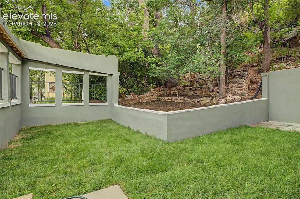 Image 34 of 38: Private outdoor space featuring a stucco wall, integrated planter box, and