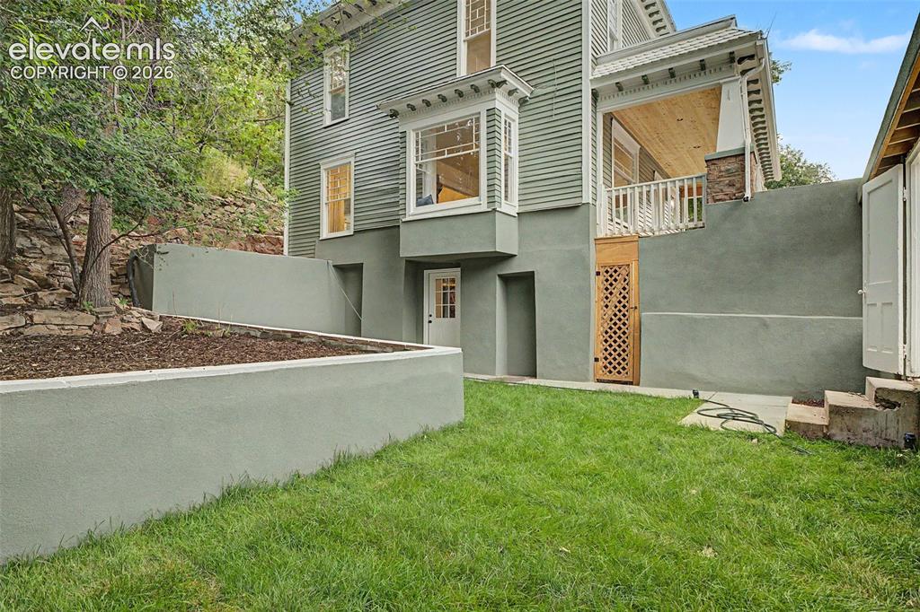 Image 35 of 38: Expansive green lawn area featuring concrete retaining walls, an exterior e