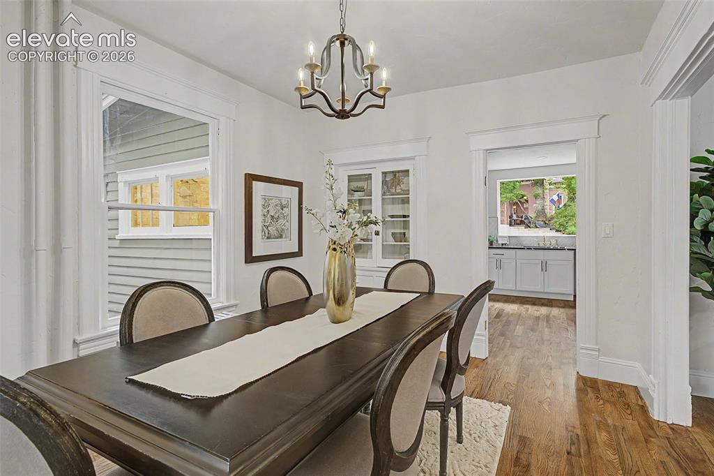 Image 9 of 38: Dining area featuring wood-finish flooring, white trim, and a decorative ch