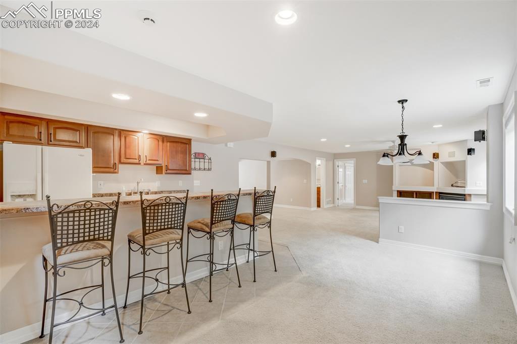 Image 23 of 40: Kitchen featuring white fridge with ice dispenser, a kitchen breakfast bar,