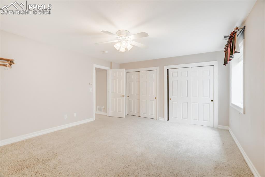 Image 33 of 40: Unfurnished bedroom featuring ceiling fan, carpet flooring, and two closets