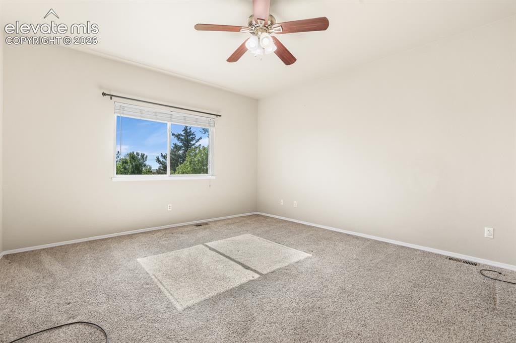 Image 11 of 37: Carpeted room featuring a ceiling fan with light fixture, a large window, a