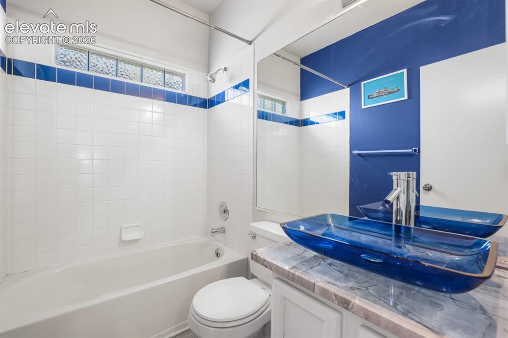 Image 16 of 37: Bathroom featuring a white bathtub, white tile surround with blue accent ba