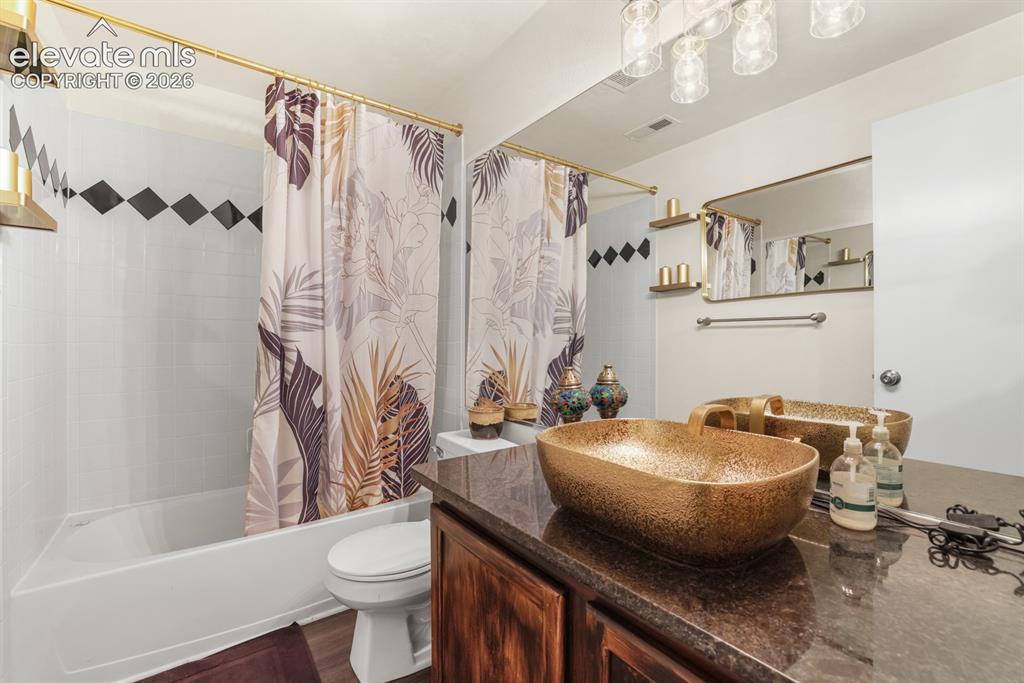 Image 25 of 37: Bathroom featuring a freestanding golden vessel sink, dark wood-finish vani