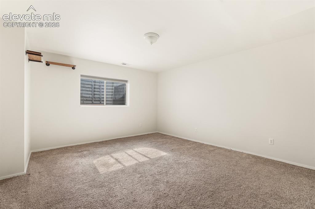 Image 26 of 37: Spacious room with light-toned walls and neutral carpet flooring