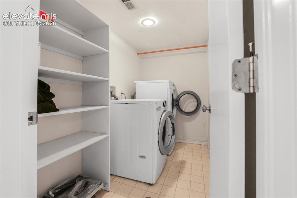 Image 28 of 37: Dedicated laundry area featuring a front-loading washer and dryer, integrat