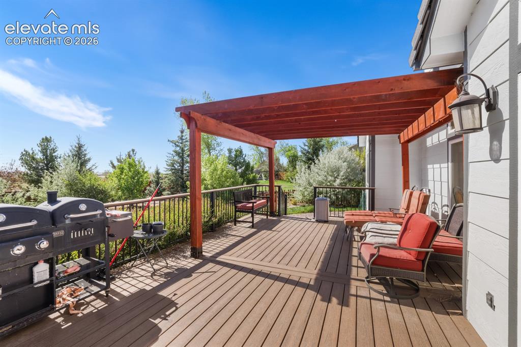 Image 29 of 37: Spacious outdoor deck featuring wood-finish decking, a red pergola structur
