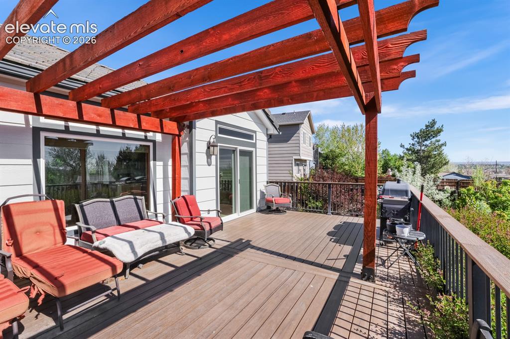 Image 30 of 37: Spacious outdoor deck featuring wood-finish flooring, a red wood pergola, a