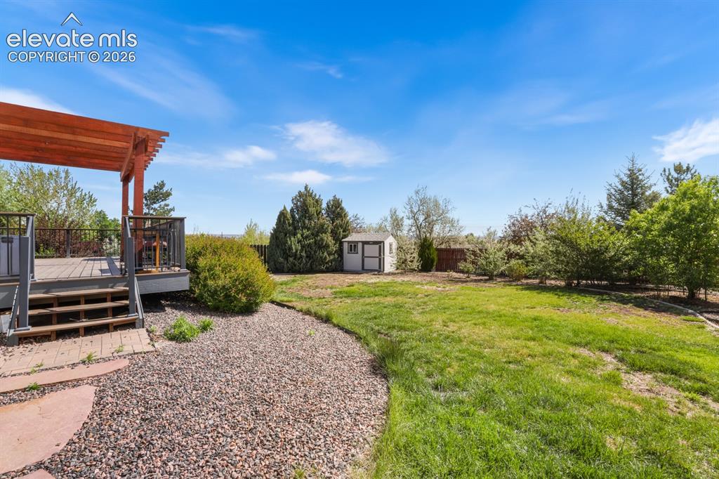Image 31 of 37: Expansive backyard featuring a multi-level deck with a wood pergola, metal 