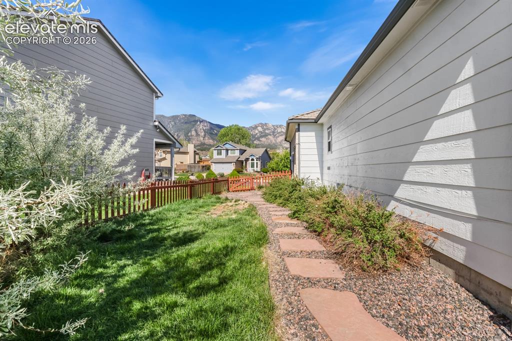 Image 32 of 37: Side yard featuring a stone pathway, low-maintenance landscaping, and a red