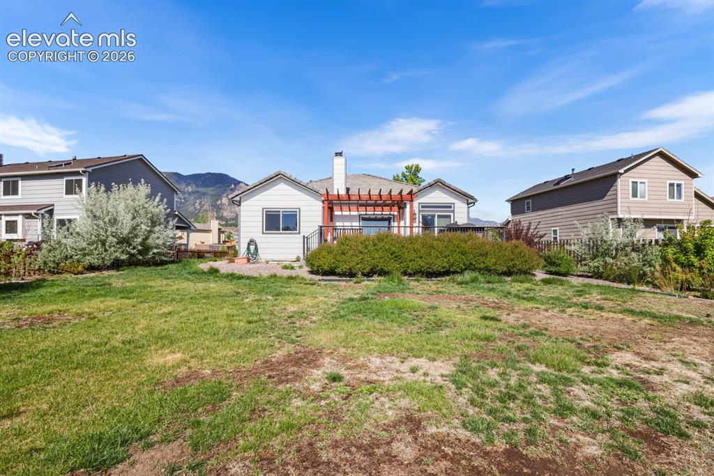 Image 34 of 37: Expansive backyard featuring a large grass area, a patio, and a pergola