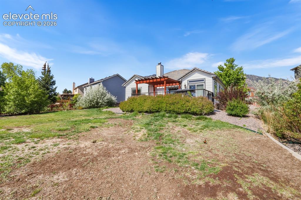 Image 35 of 37: Expansive sloped yard featuring a paved patio area, an upper wood deck with