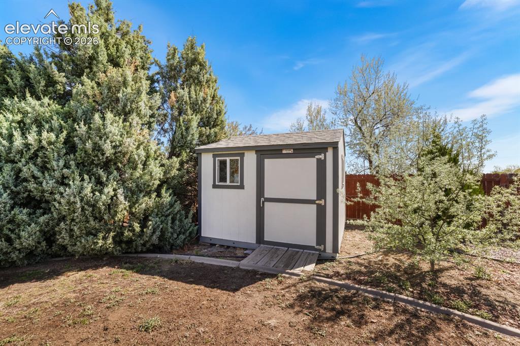 Image 36 of 37: Storage shed featuring a shingled roof, white siding, and dark trim