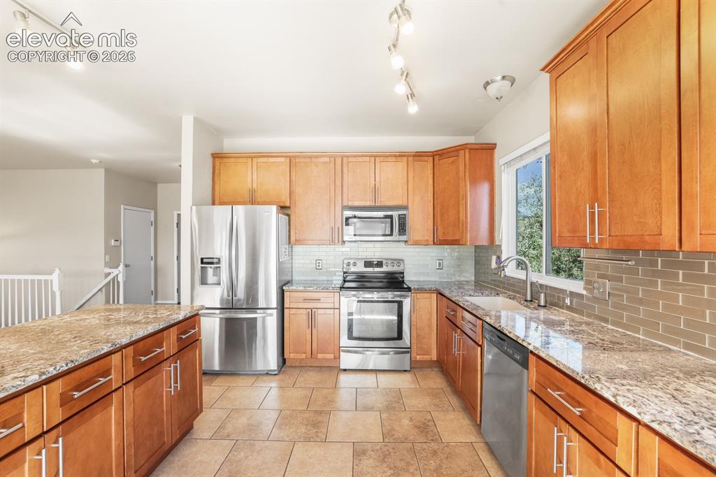 Image 8 of 37: Open-concept kitchen featuring wood cabinetry, stainless steel appliances, 