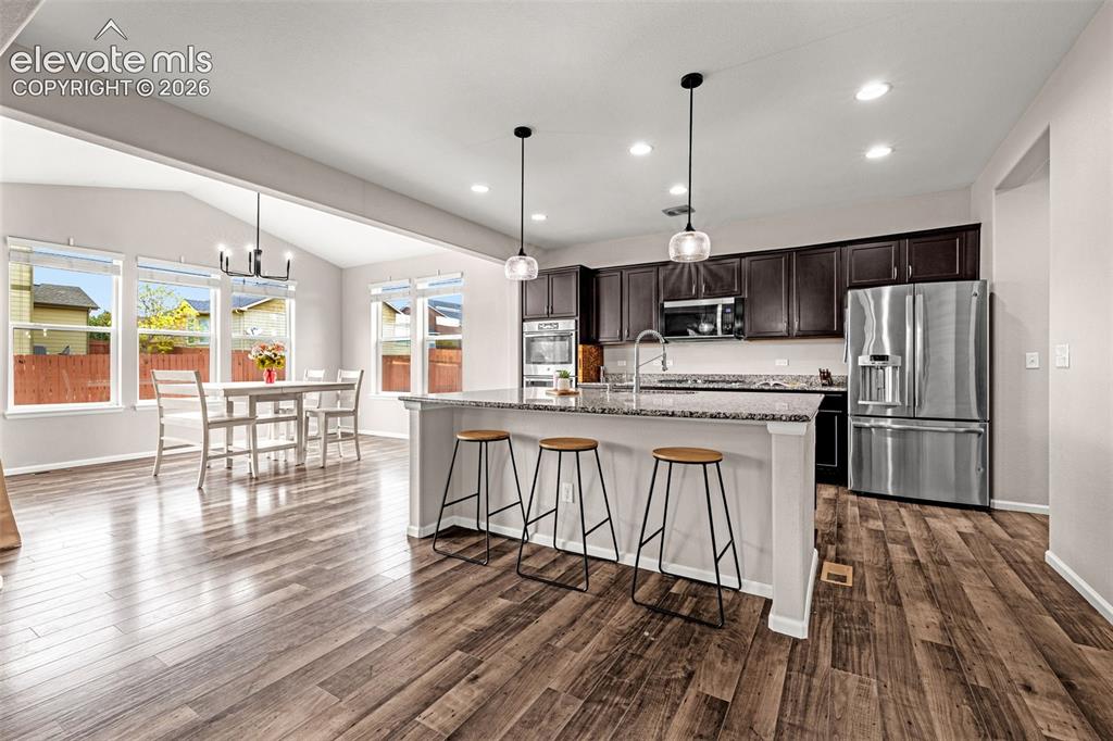 Image 10 of 49: Open-concept kitchen and dining area featuring wood-finish flooring, dark w