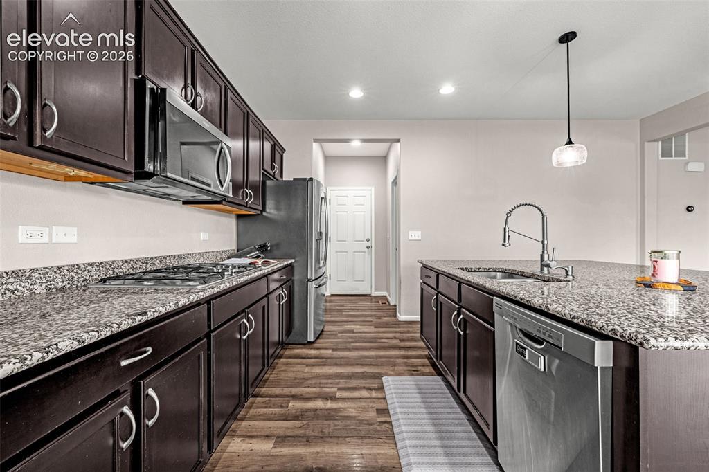 Image 11 of 49: Contemporary kitchen featuring dark wood cabinetry, light-toned countertops