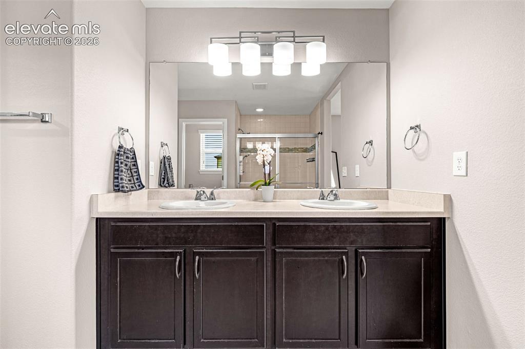 Image 20 of 49: Double vanity with dark wood-finish cabinetry, dual undermount sinks, and a