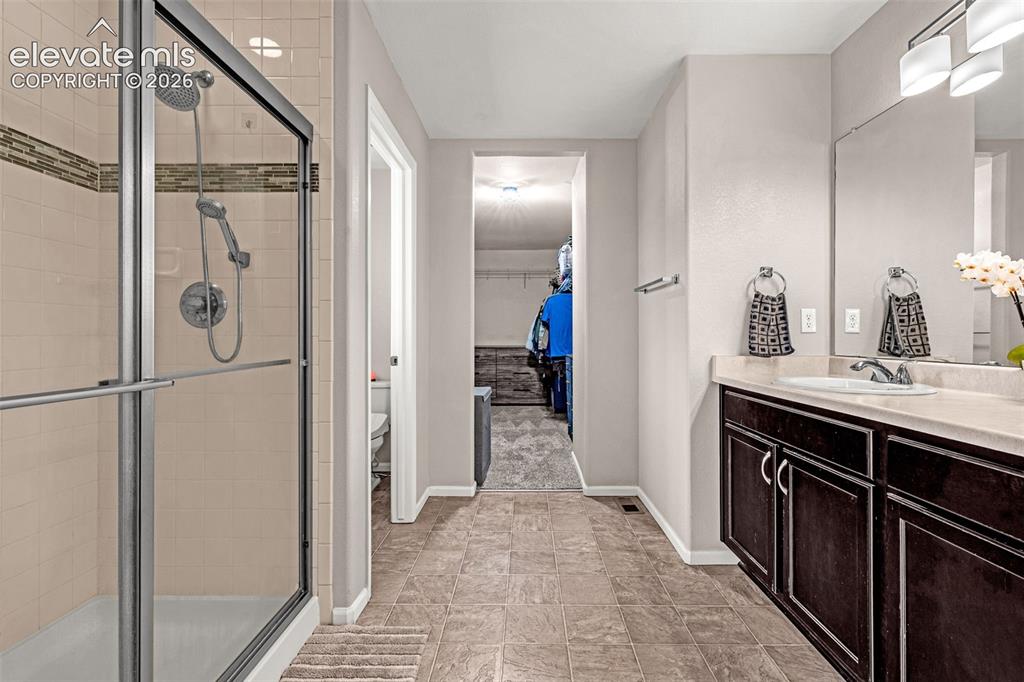 Image 21 of 49: Bathroom featuring a glass-enclosed shower with tile surround, dual shower