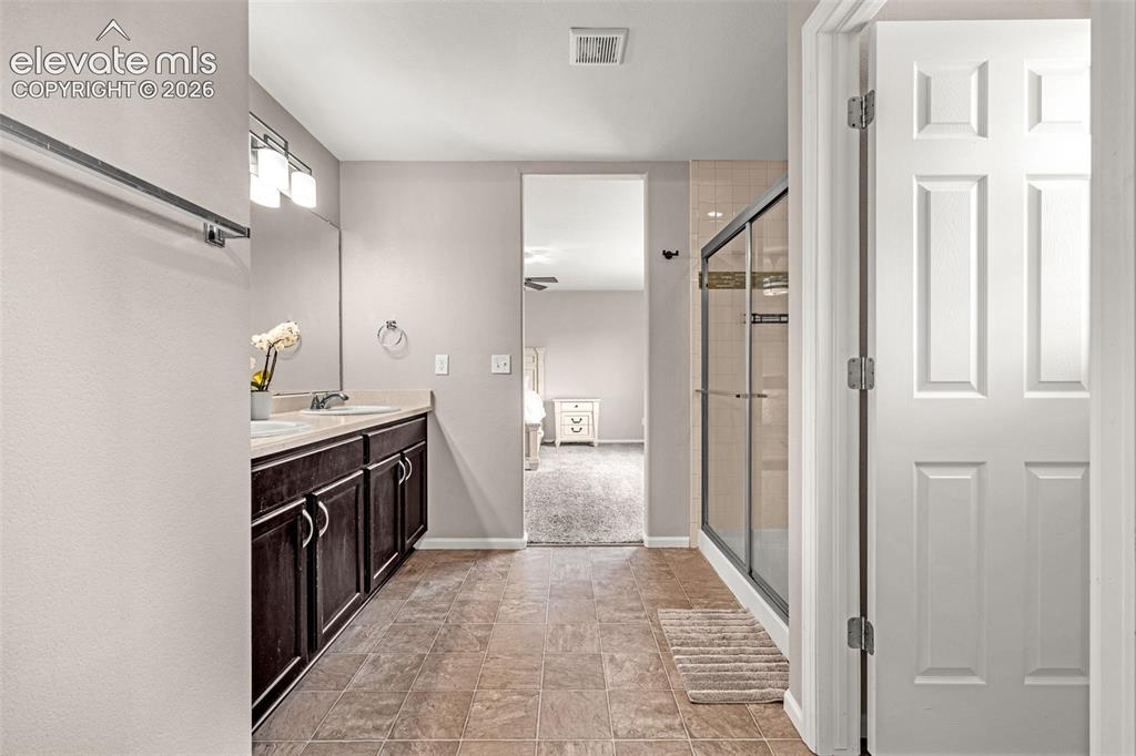 Image 22 of 49: Bathroom featuring a double vanity with dark wood cabinetry and dual sinks,