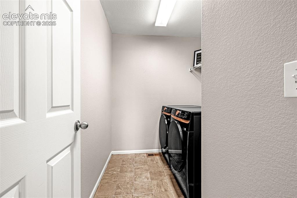 Image 27 of 49: Dedicated utility space featuring tile flooring and a wall-mounted shelf