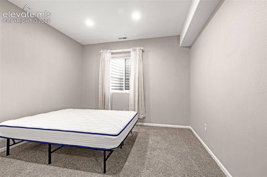 Image 30 of 49: Carpeted room featuring a window with horizontal blinds, recessed lighting,