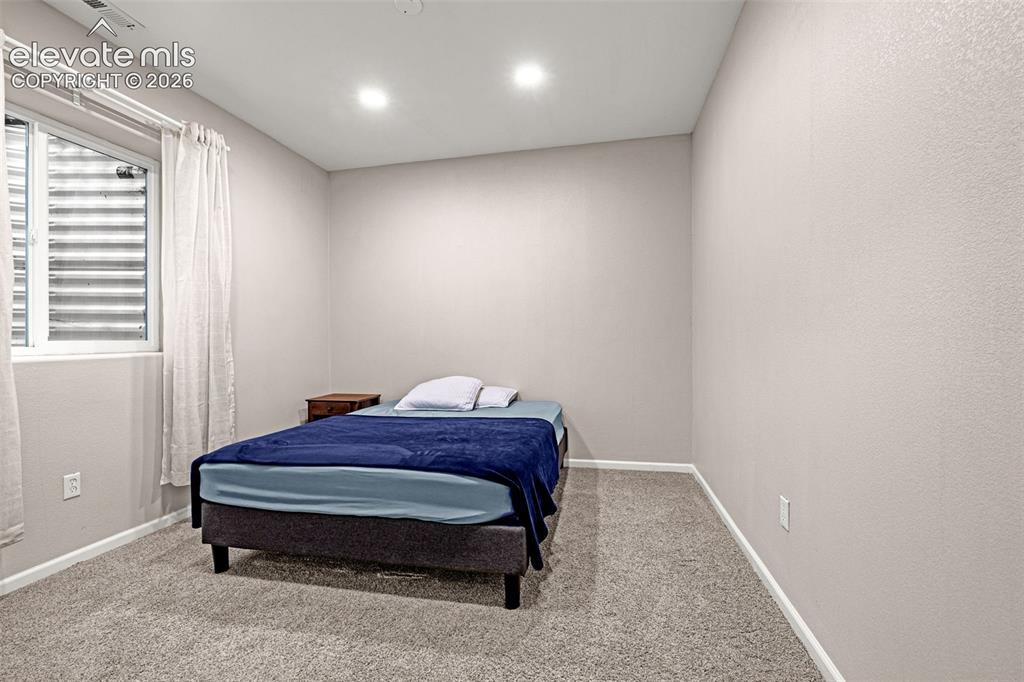 Image 31 of 49: Carpeted room with recessed lighting and a window featuring horizontal blin