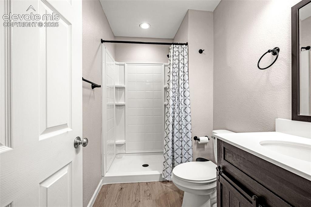 Image 32 of 49: Bathroom featuring a single-piece shower with built-in shelving, a dark woo