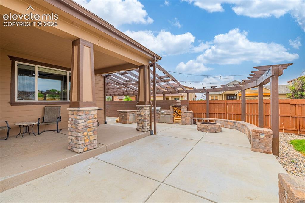 Image 34 of 49: Expansive concrete patio featuring a stone-clad outdoor kitchen, built-in f