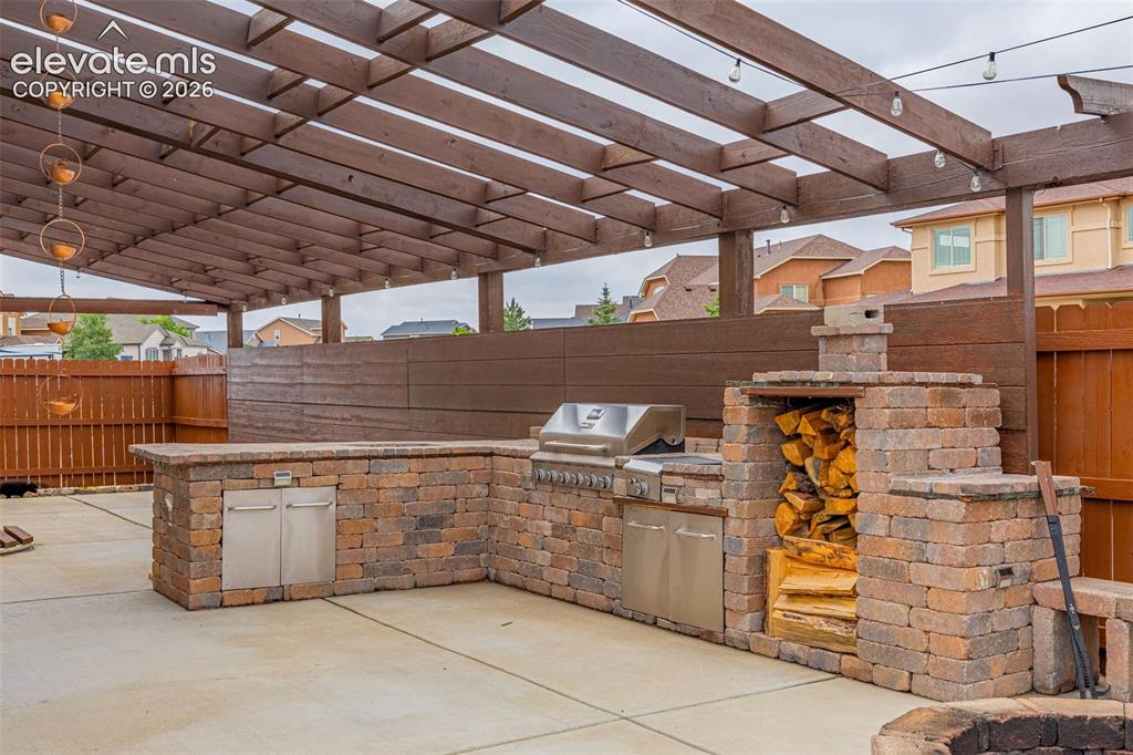 Image 35 of 49: Outdoor kitchen featuring stone block construction, built-in grill, and sta