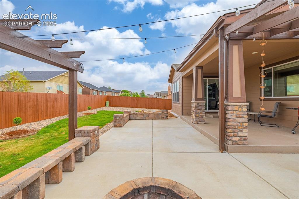 Image 37 of 49: Expansive concrete patio featuring a built-in fire pit, stone seating, and