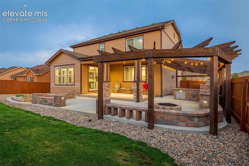 Image 38 of 49: Expansive backyard featuring a concrete patio, a wooden pergola with string