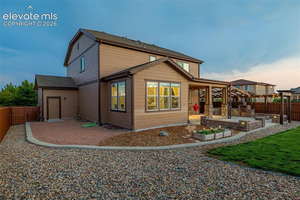 Image 39 of 49: Expansive rear exterior featuring a covered patio, built-in outdoor kitchen
