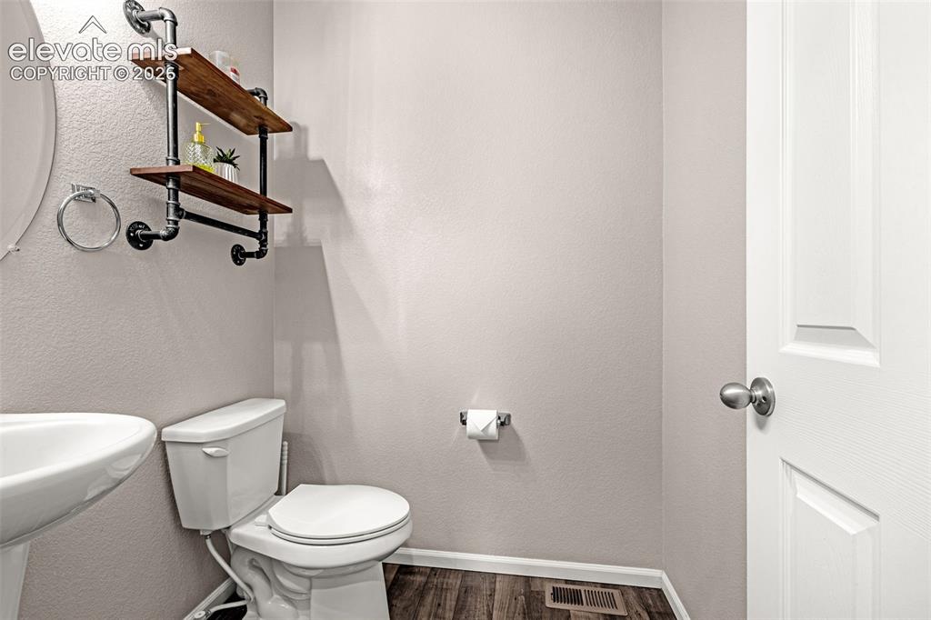 Image 5 of 49: Bathroom featuring a white pedestal sink and toilet, wood-finish flooring,