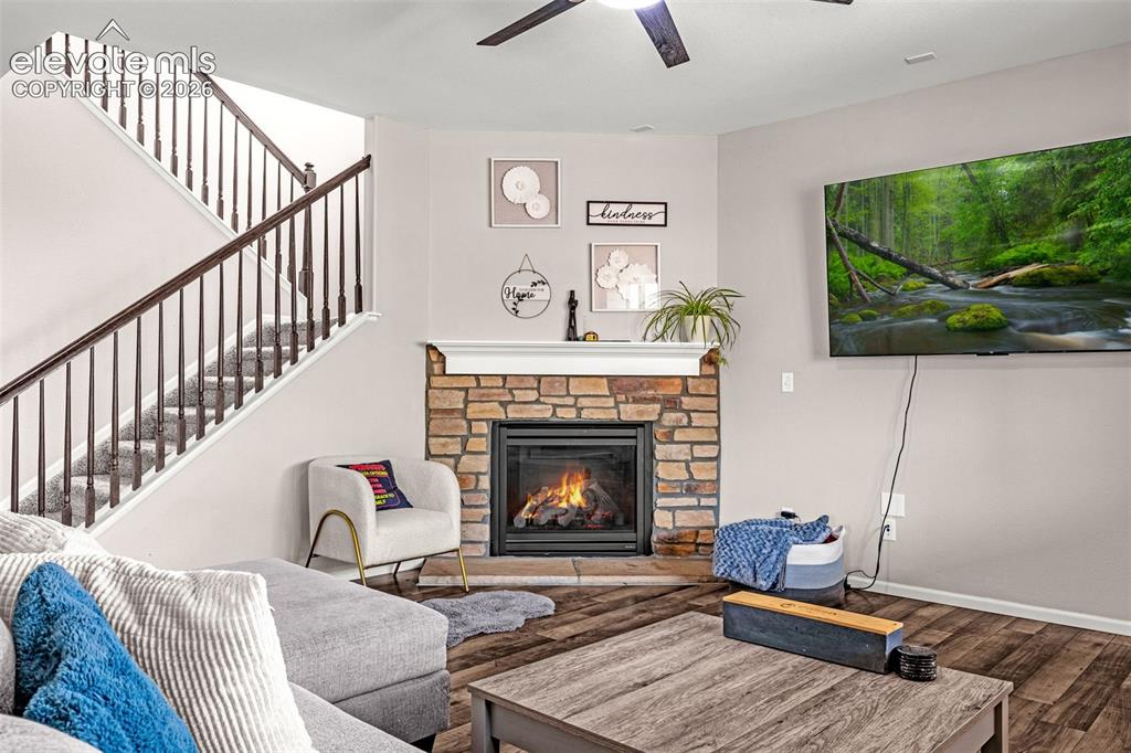 Image 7 of 49: Living area featuring a stone-clad fireplace with a white mantel, wood-fini
