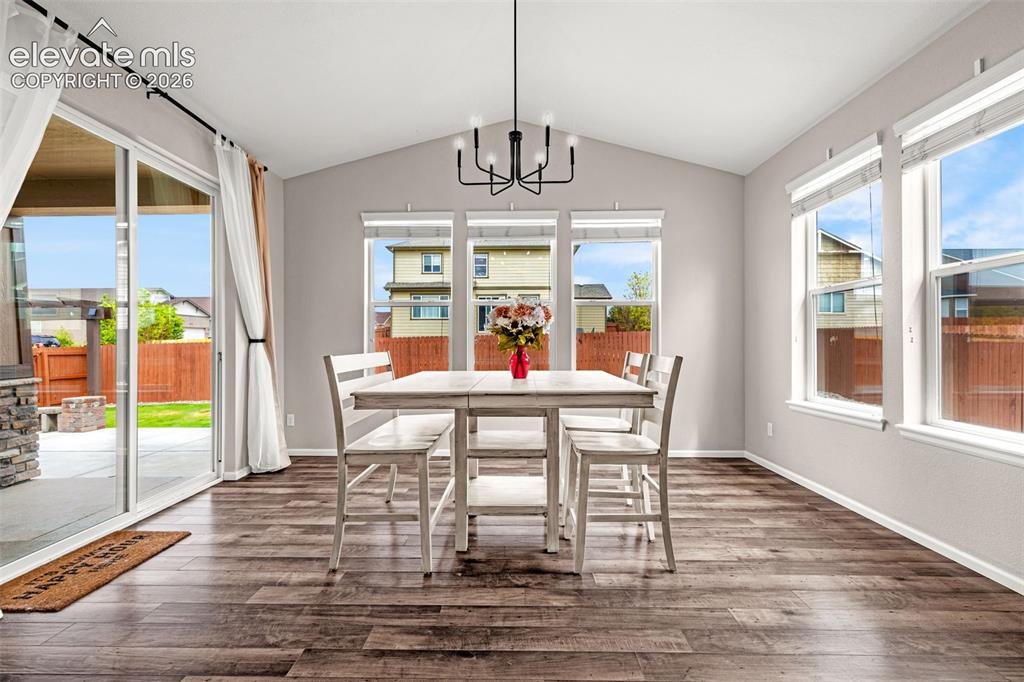 Image 9 of 49: Vaulted ceiling dining area featuring a modern chandelier, multiple large w