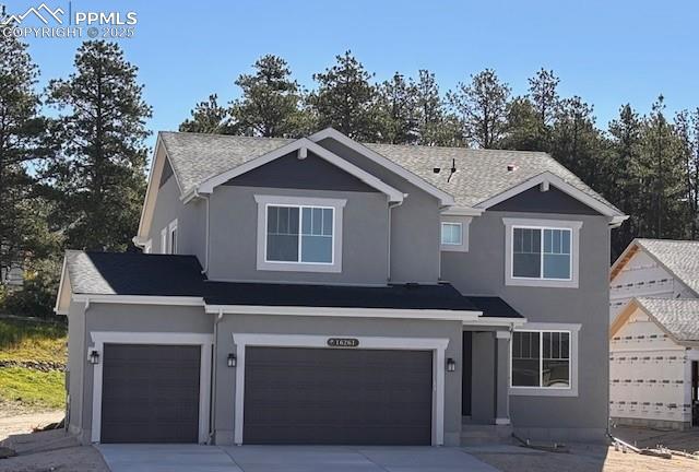 Caption: View of front of house featuring driveway, stucco siding, and a garage