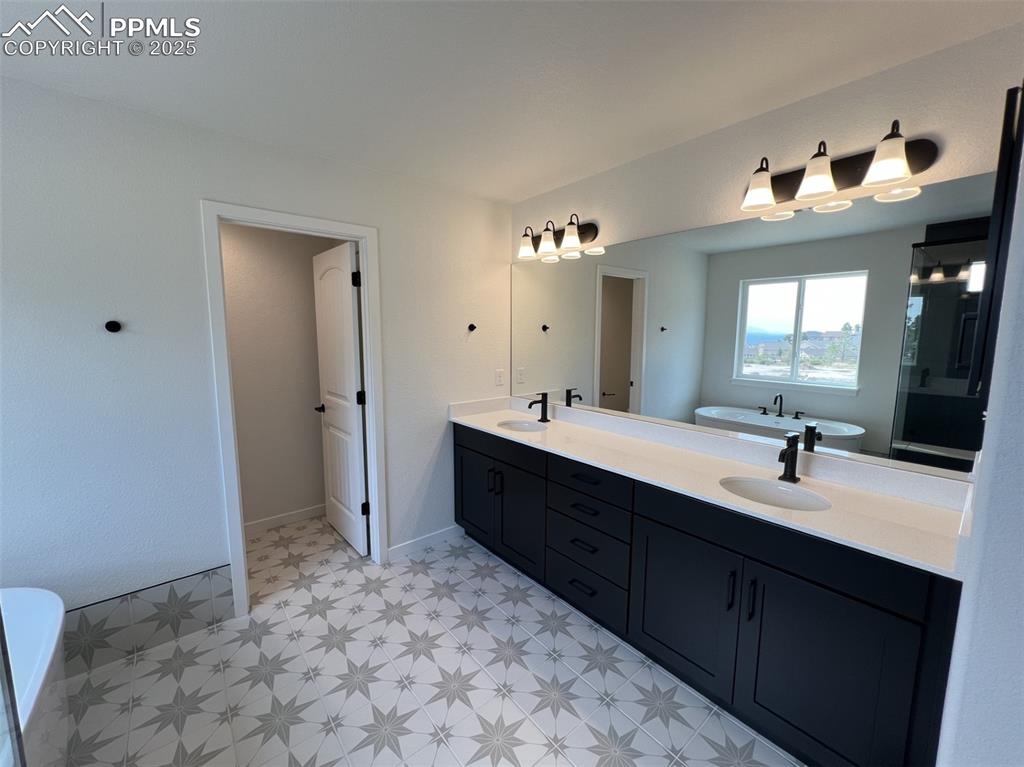 Image 10 of 17: Bathroom featuring a soaking tub, double vanity, and light floors